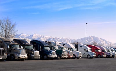 Des cabines de semi-remorques alignées sur un parking avec des montagnes en arrière-plan